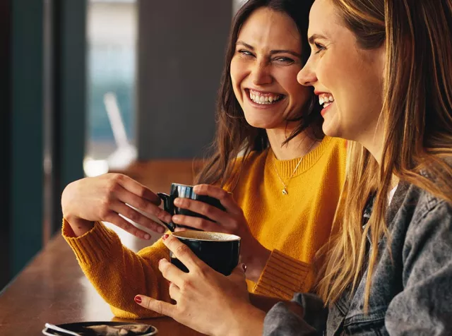 Immagine di due ragazze che bevono un caffè sorridendo. Usare i Buoni Pasto Pluxee per la tua pausa pranzo è davvero semplice e comodo. 