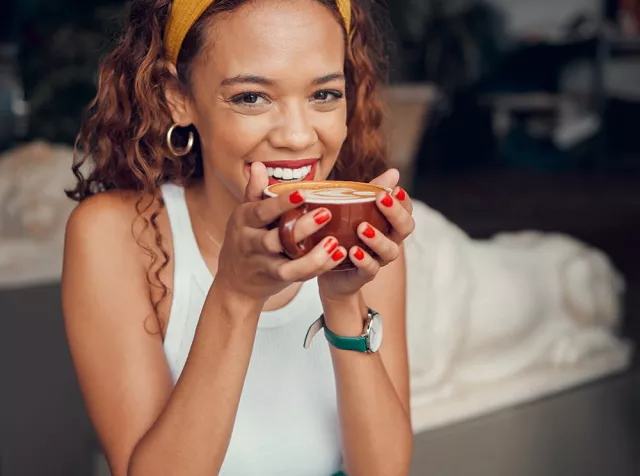 Immagine di una ragazza che sorride bevendo un cappuccino. Con i Buoni Pasto Cartacei Pluxee approfitti di un mondo di vantaggi.
