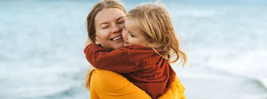 Immagine di una mamma che abbraccia teneramente la sua bambina, simboleggiando i nostri servizi di welfare dedicati al benessere dei dipendenti.